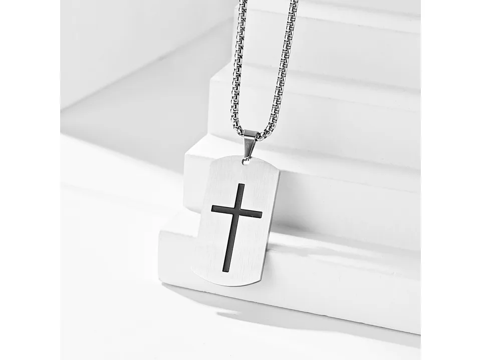 Silver dog tag necklace with a cross cutout on a white tiered display.