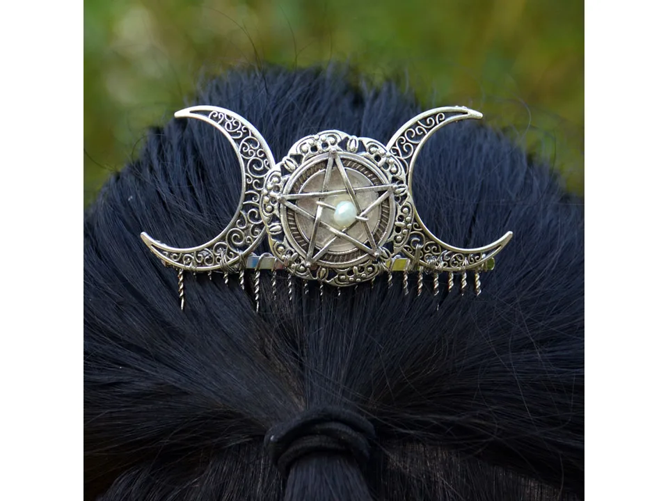 A silver pentagram and moon hair comb worn in dark hair.