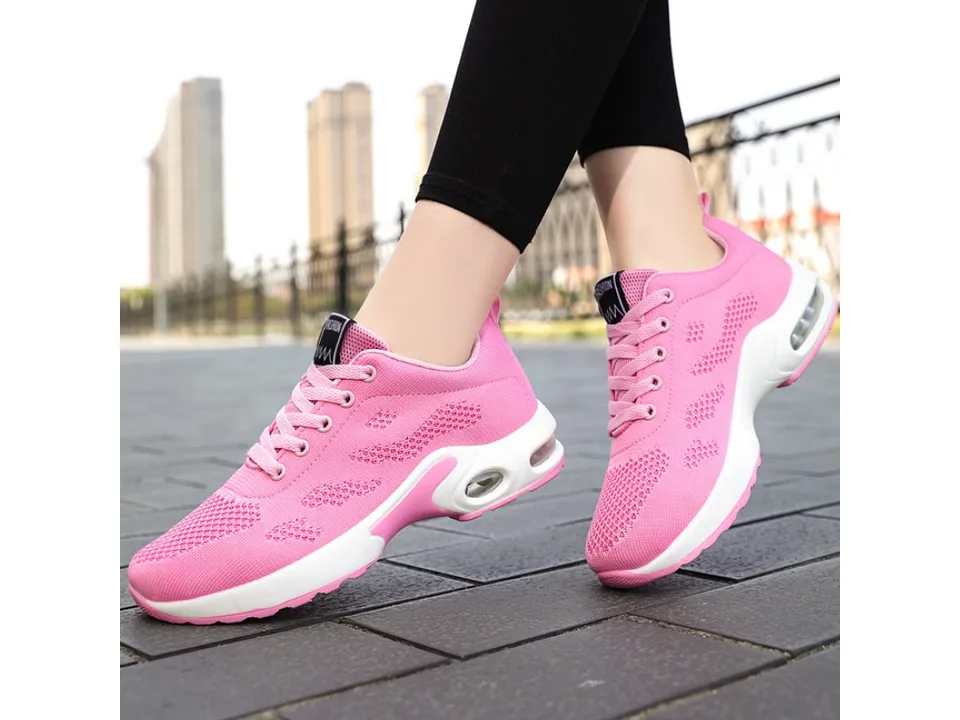 A person wearing pink athletic sneakers outdoors.