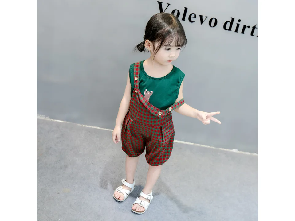 A young girl wearing the green and red plaid bib overalls set.