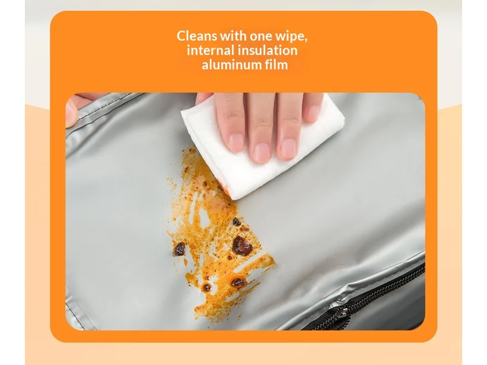 A hand wiping the interior aluminum lining of the lunch bag with a cloth.