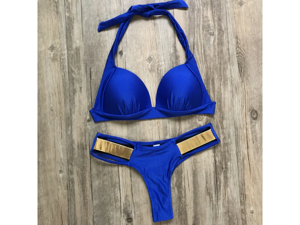Blue bikini set with gold metallic side details laid out on a wooden surface.