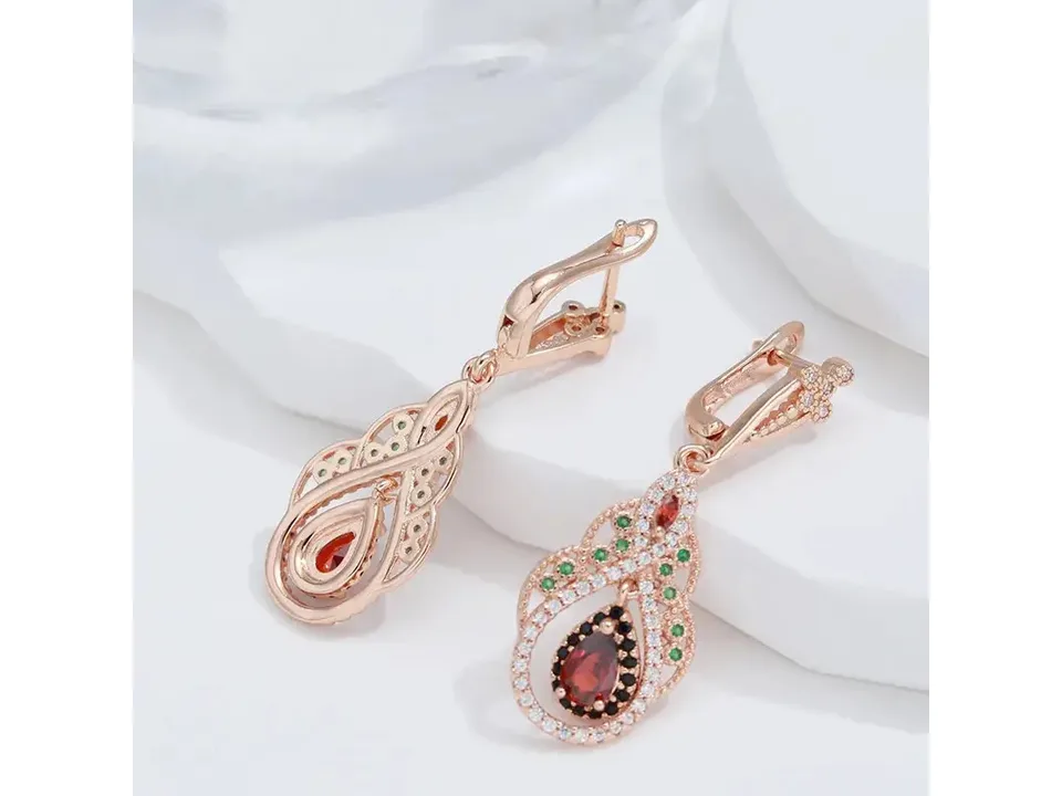 A pair of rose gold bohemian drop earrings with red, green, and clear cubic zirconia stones on a white background.