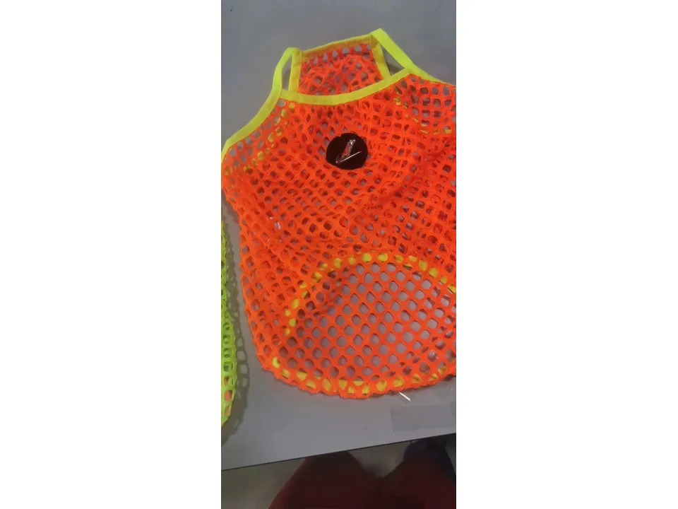 An orange mesh dog vest with a circular logo patch.