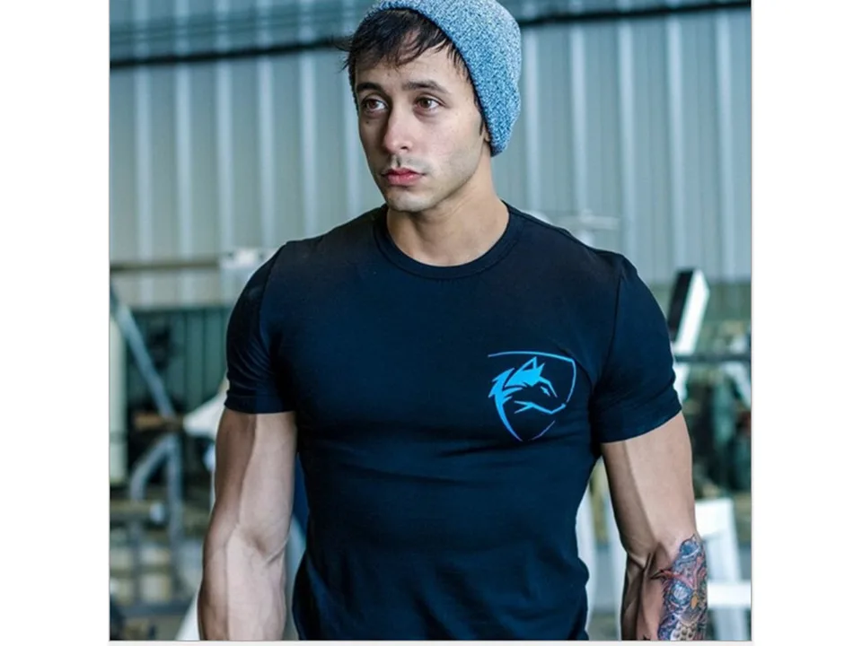 A man wearing a black slim-fit sports t-shirt with a blue wolf logo.
