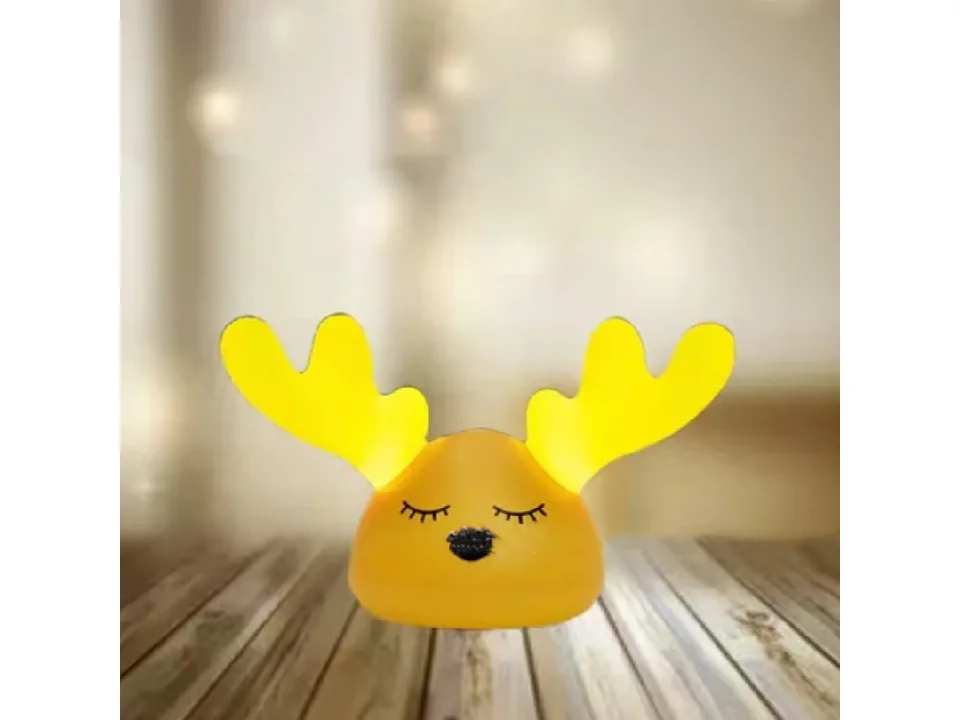 The deer night light glowing with yellow light on a wooden surface.