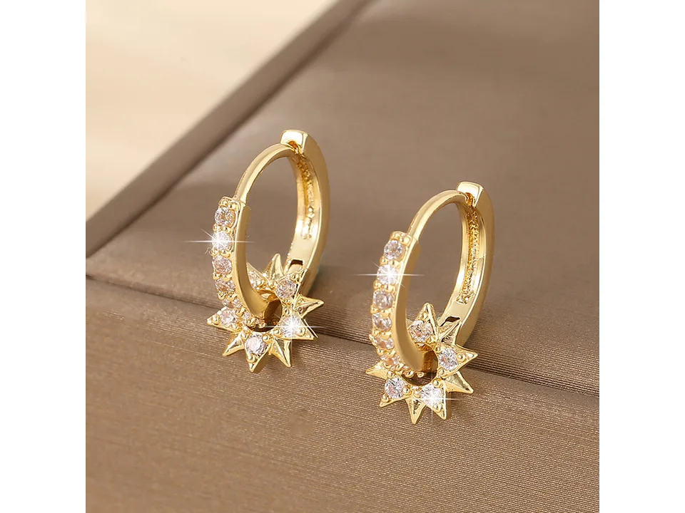 Close-up of two gold star hoop earrings with crystal accents.