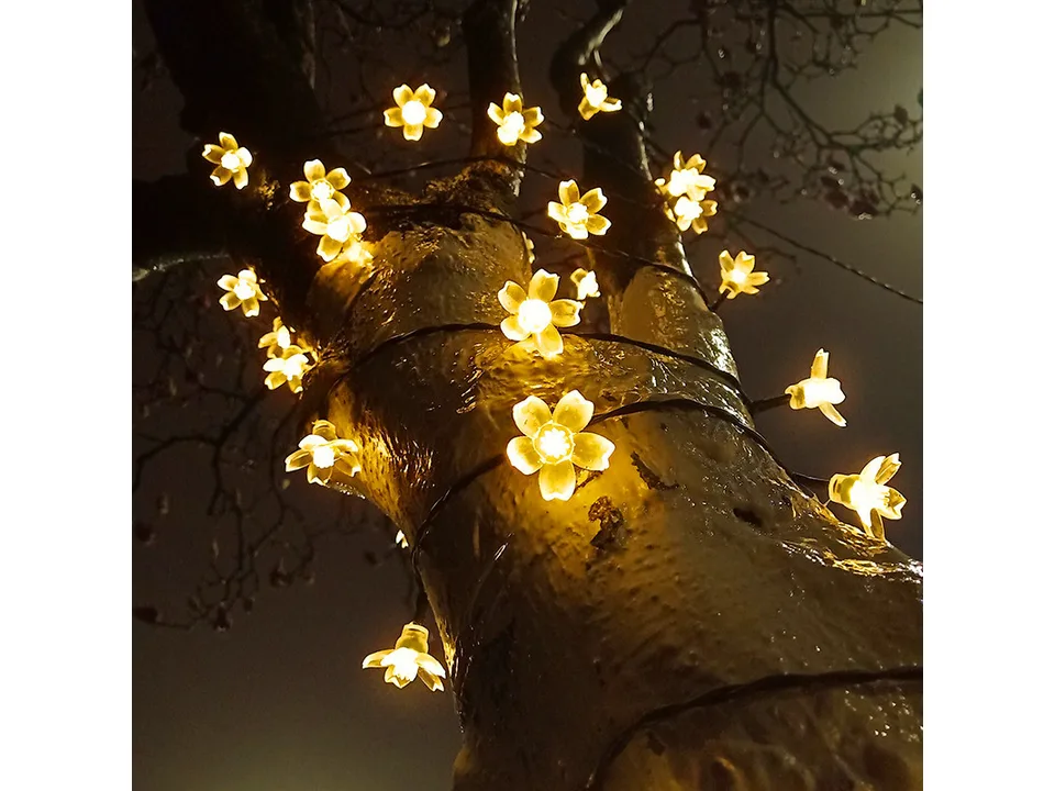 Solar sakura flower string lights wrapped around a tree trunk at night