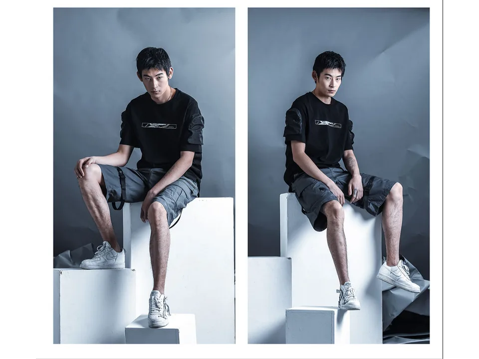 A model wearing the grey tactical cargo shorts while sitting on white blocks.