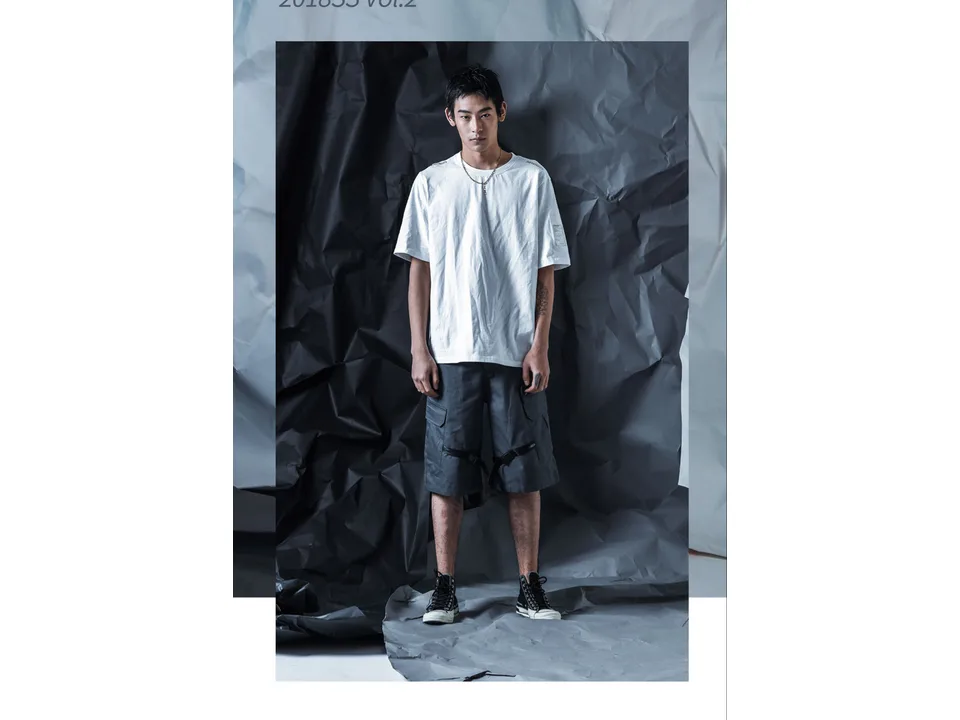 A model standing and wearing the grey cargo shorts with a white t-shirt.