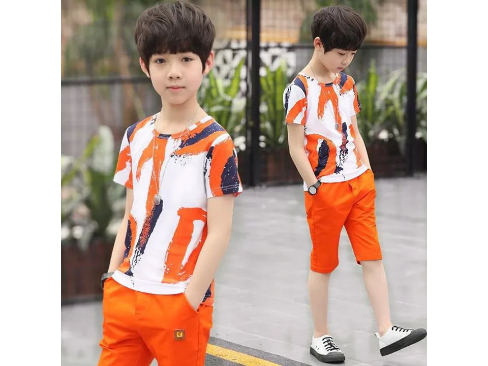 A boy wearing an orange and white patterned t-shirt and orange shorts.