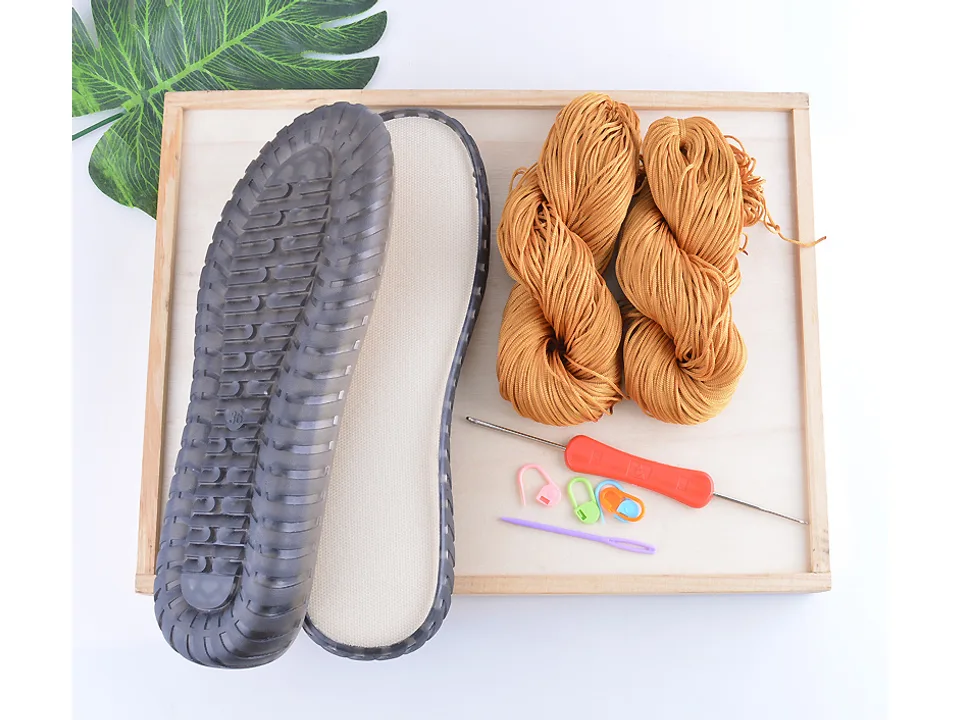 DIY shoe making kit with rubber sole, yarn, crochet hook, and stitch markers.