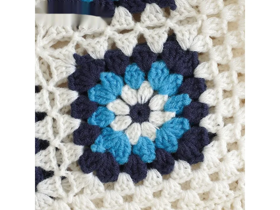 Detailed view of the blue and white floral crochet pattern on the sweater.