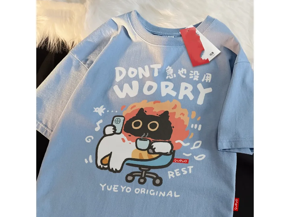Light blue oversized t-shirt with a graphic of a cat sitting in a chair with a phone and coffee.