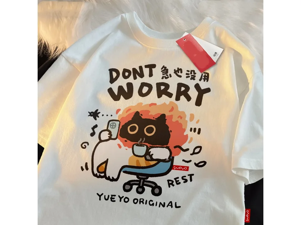 White oversized t-shirt with a graphic of a cat sitting in a chair with a phone and coffee.