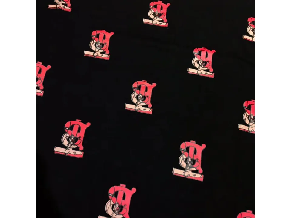 Close-up of the fabric showing the red letter print pattern on a black background.
