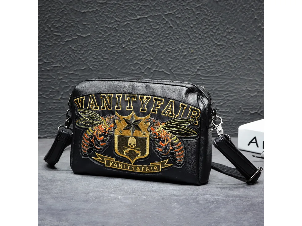 Black embroidered crossbody bag sitting on a grey surface.