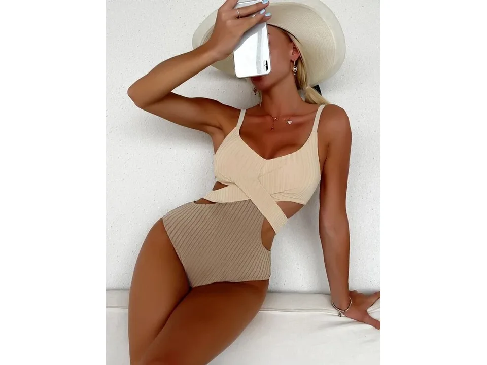A woman wearing a beige and brown ribbed one-piece swimsuit with crisscross detail.