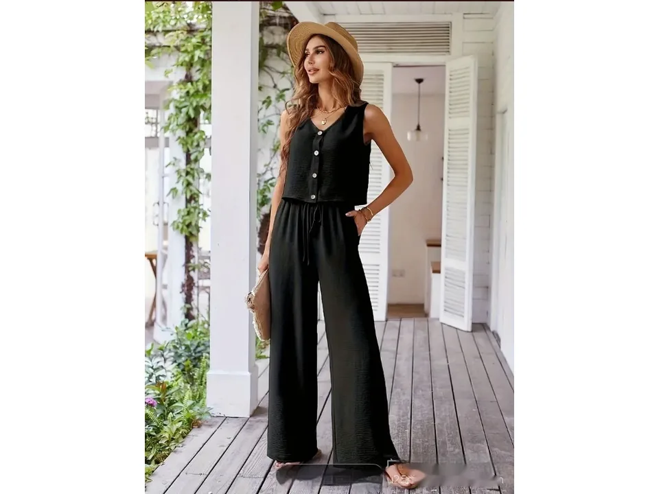 A woman wearing a black vest and wide-leg pants, with her hand in her pocket.