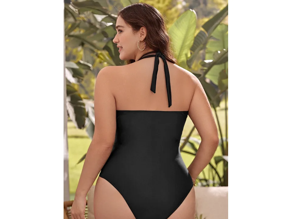 Back view of a woman wearing a black halter-neck one-piece swimsuit.