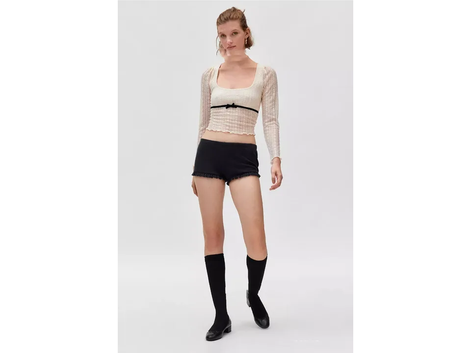 A model wearing the cream lace mesh top with black shorts and knee-high socks.