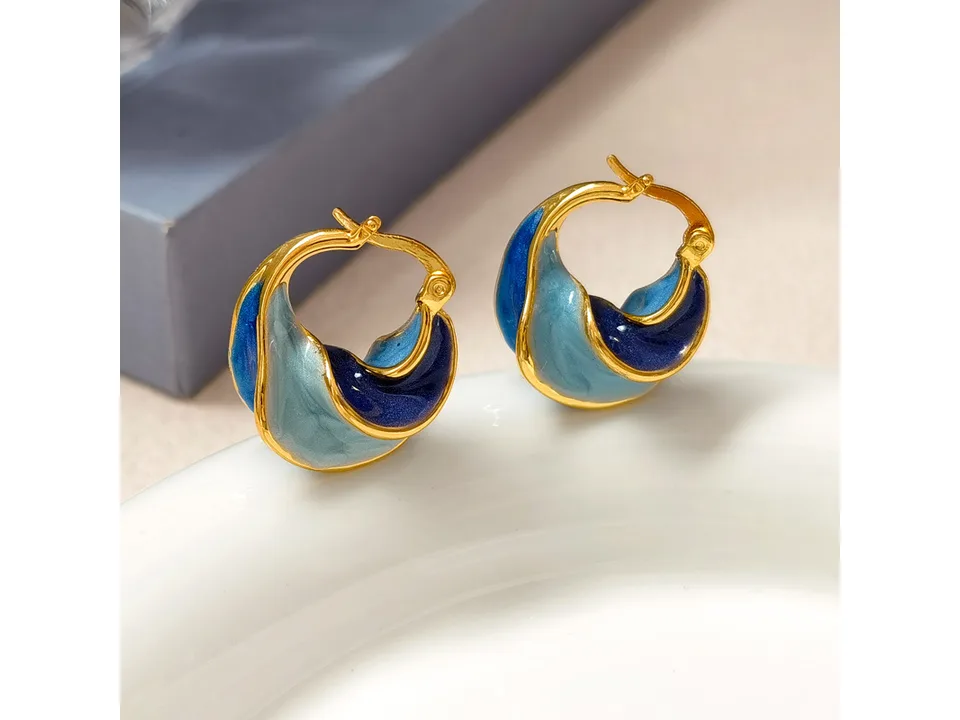 Close-up of the blue and gold spiral hoop earrings resting on a white surface.