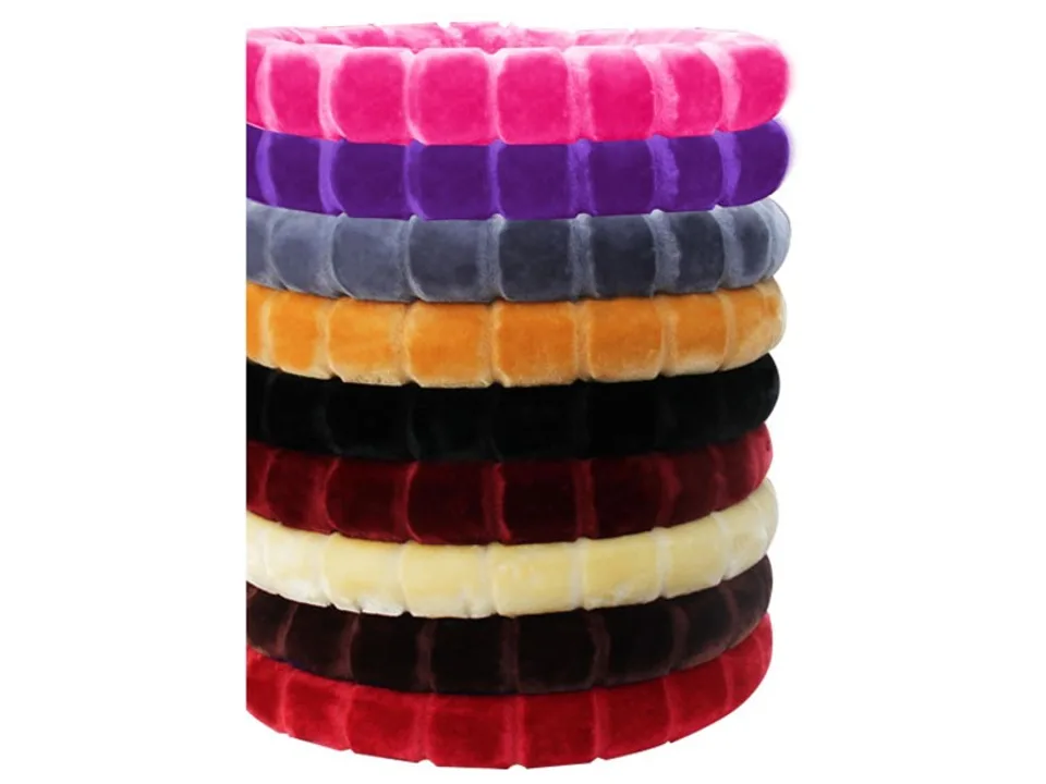 A stack of plush steering wheel covers in various colors including pink, purple, grey, orange, black, and red.