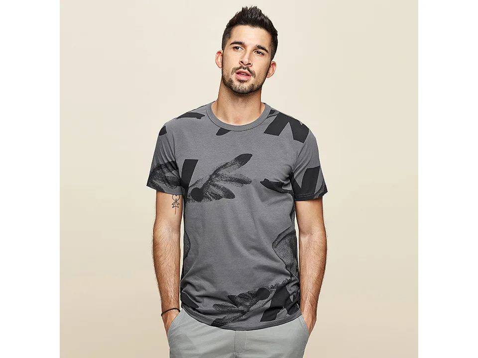 A man wearing a grey t-shirt with a black abstract print.