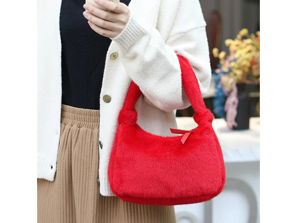 A person holding a red furry mini handbag.