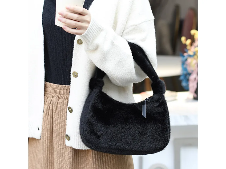 A person holding a black furry mini handbag.