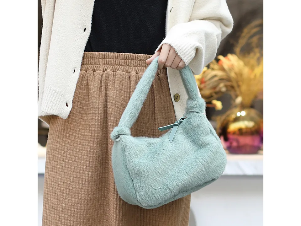 A person holding a light green furry mini handbag.