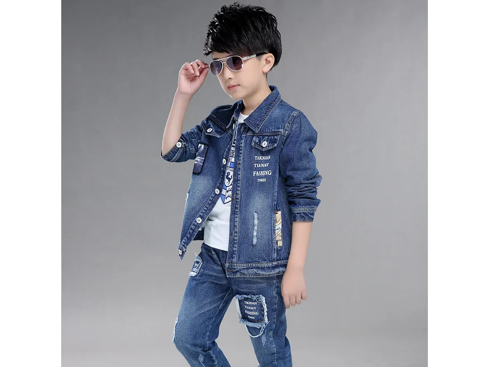 A boy wearing a denim jacket and jeans outfit.