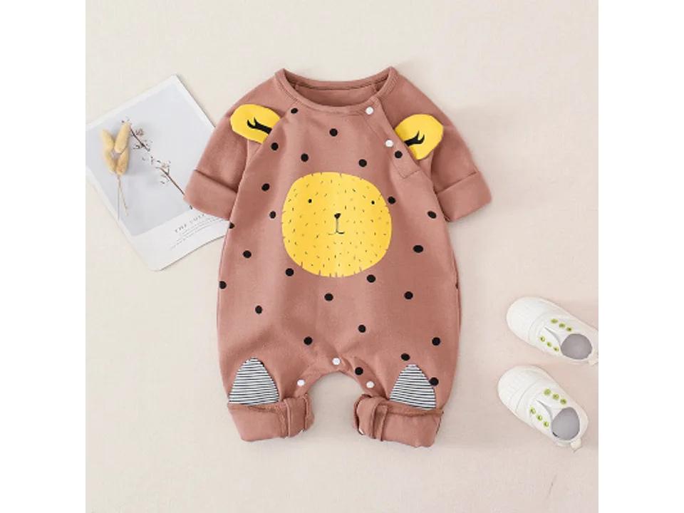 Brown infant jumpsuit with yellow animal face graphic and polka dots, displayed with baby shoes.