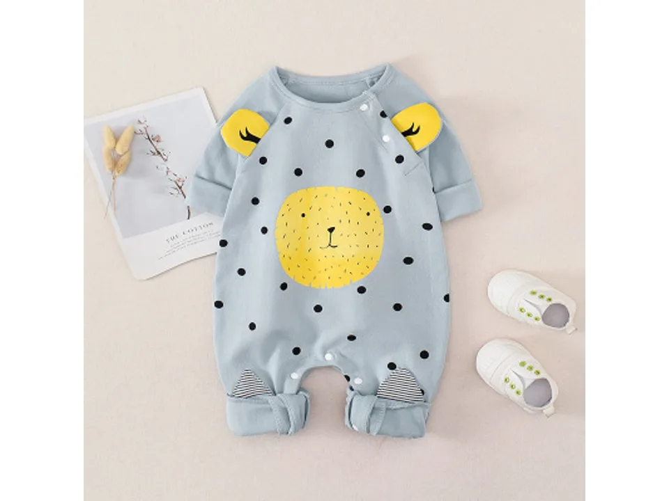 Blue infant jumpsuit with yellow animal face graphic and polka dots, displayed with baby shoes.