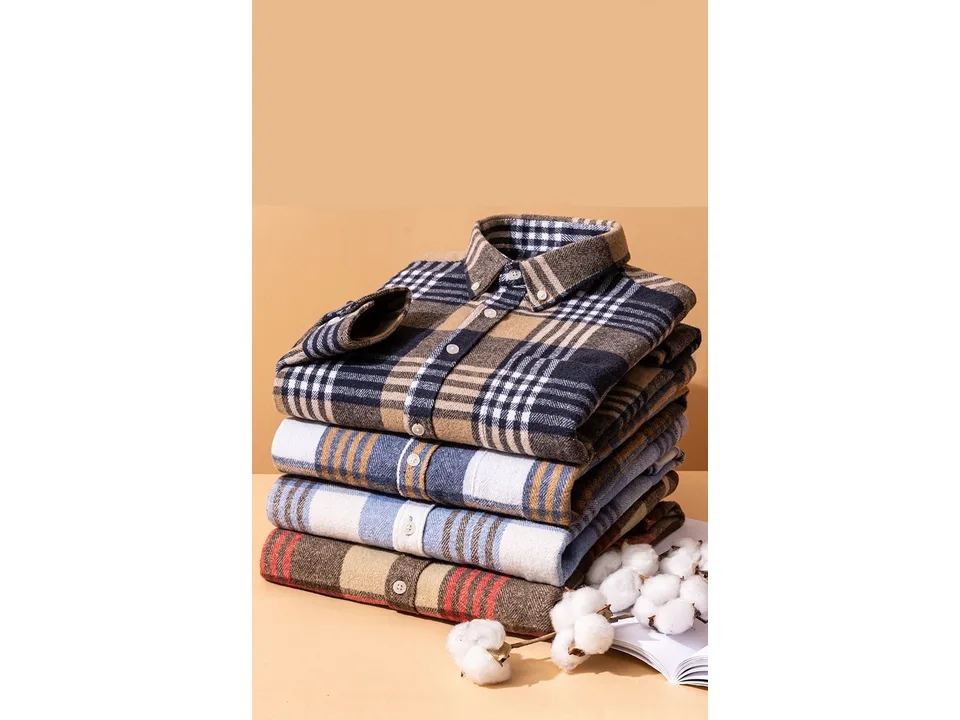 A stack of folded plaid shirts in different colors with cotton bolls.