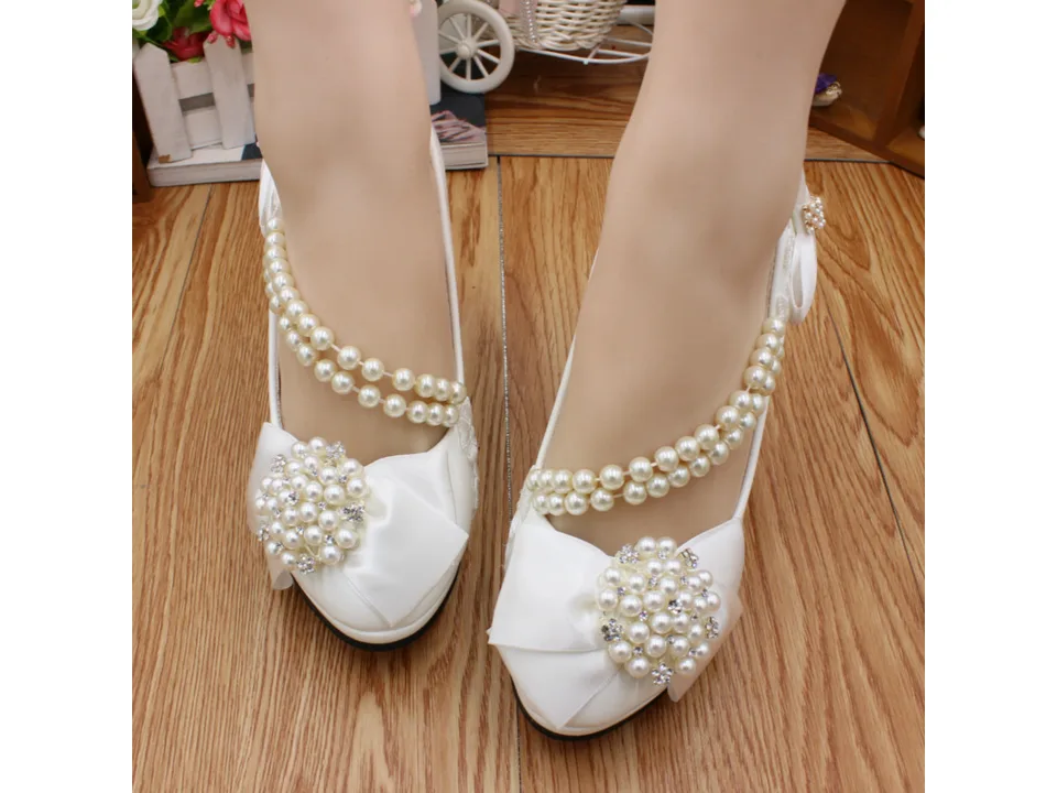 Front view of white bridal heels with pearl straps and decorative pearl clusters.