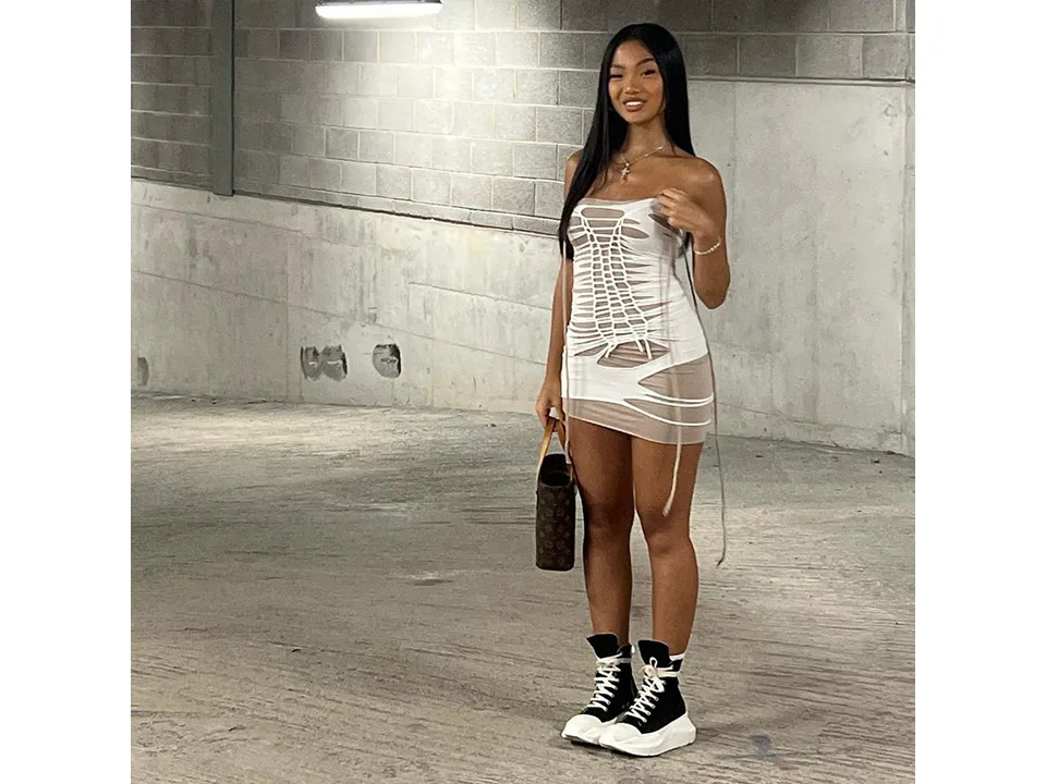 A model standing and wearing a white lace-up mini dress.