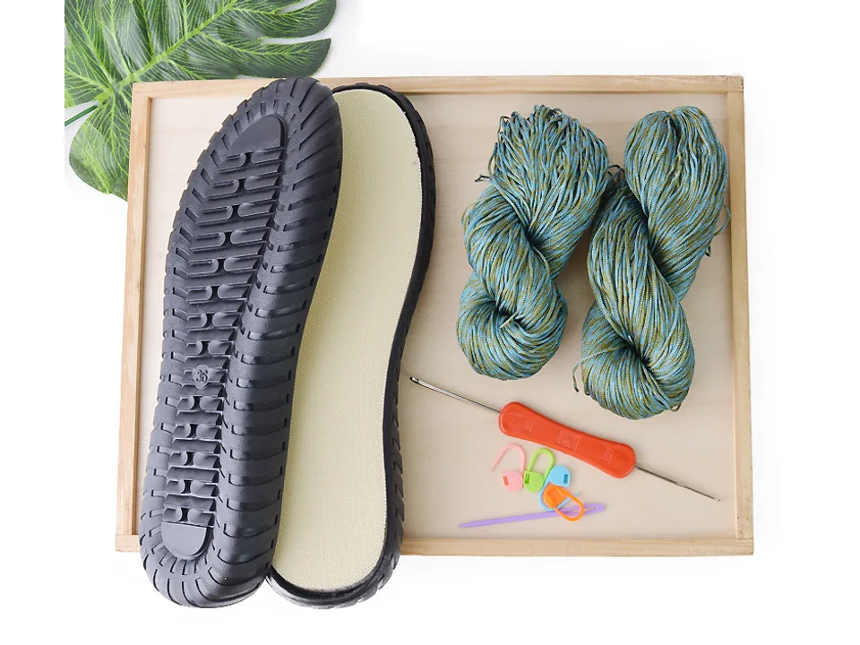 DIY crochet shoe kit including a black sole, blue-green yarn, crochet hook, and stitch markers.