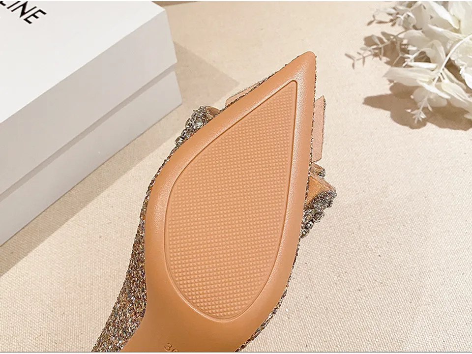 Close-up view of the textured sole of a silver stiletto pump.
