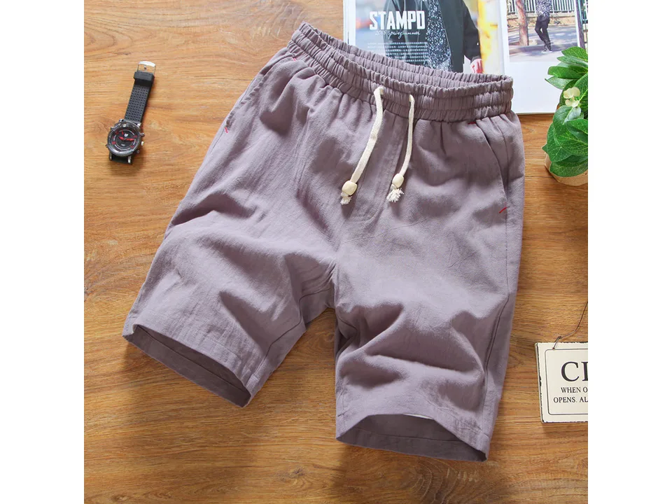 Purple casual linen shorts with drawstring waistband laid flat on a wooden surface.