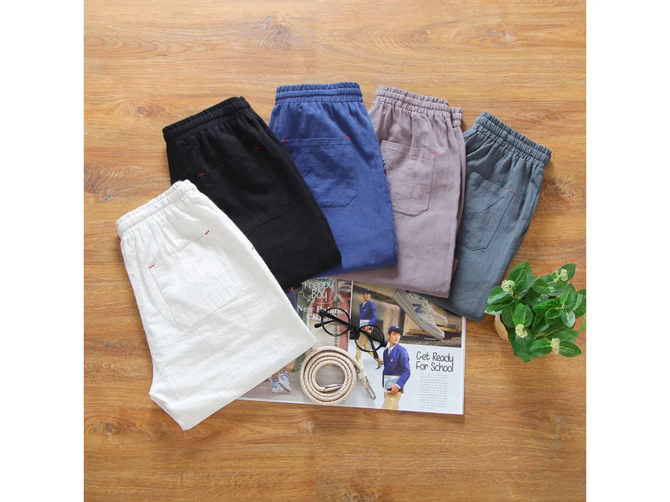 A collection of casual linen shorts in various colors laid out on a wooden surface.
