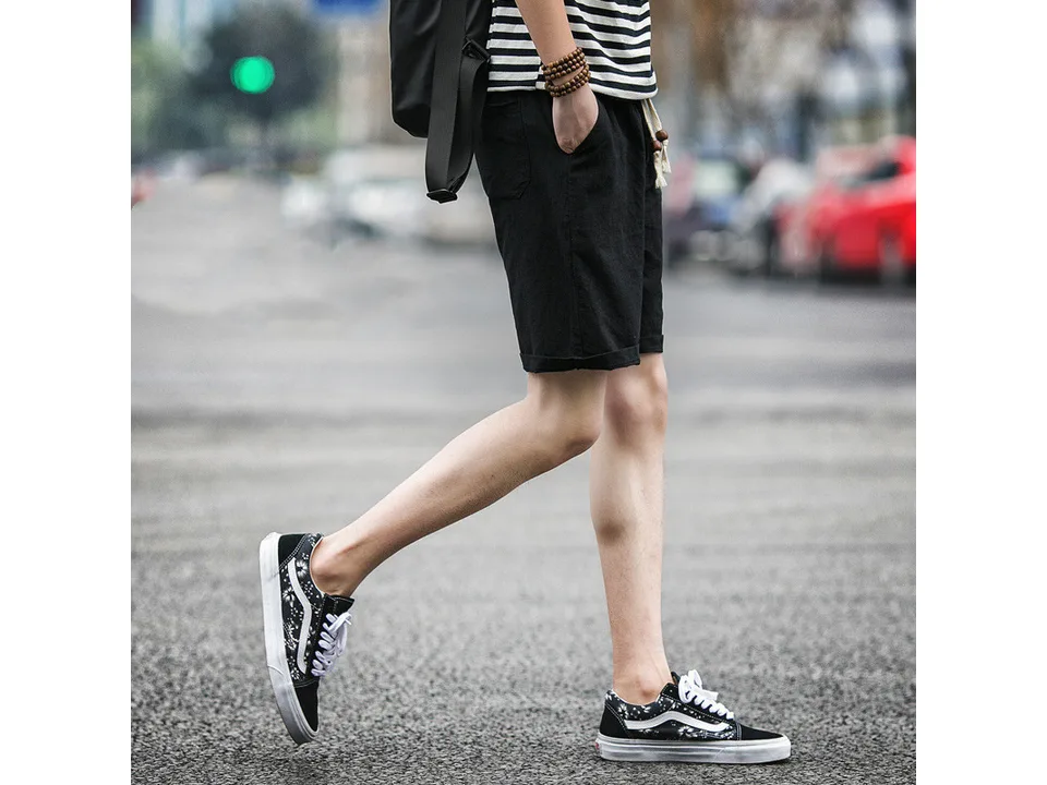 A person wearing black casual linen shorts, viewed from the side.