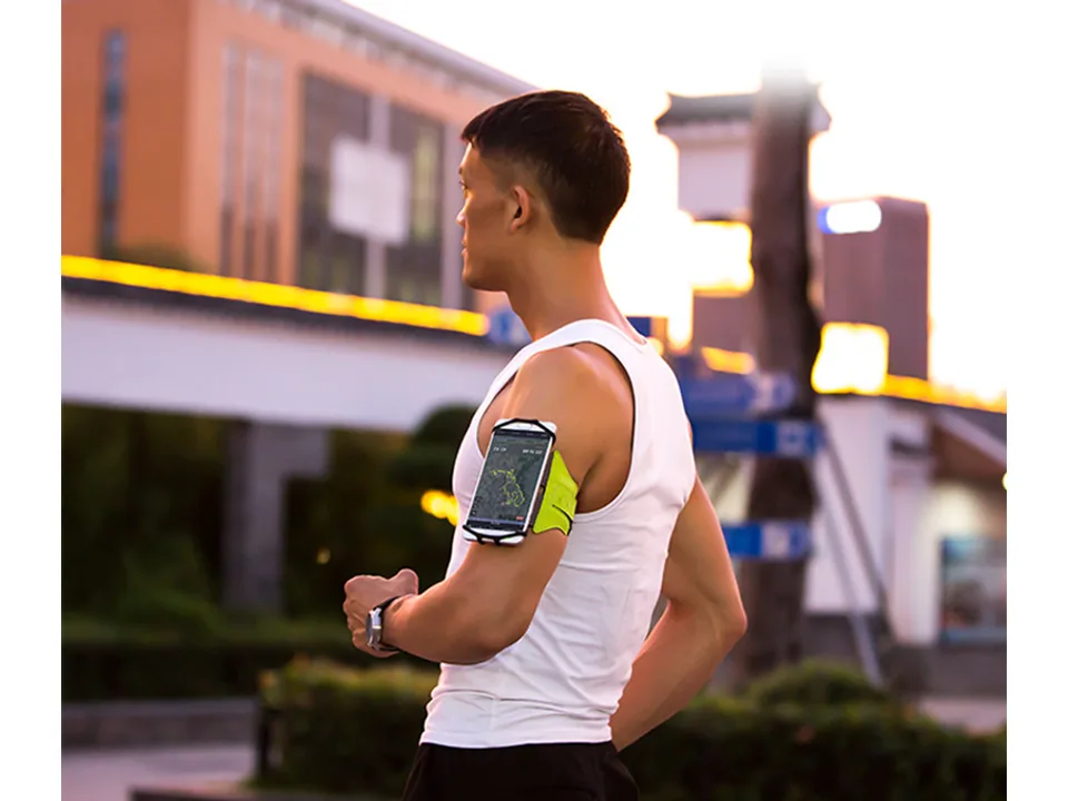 A man running outdoors wearing the phone armband on his arm.
