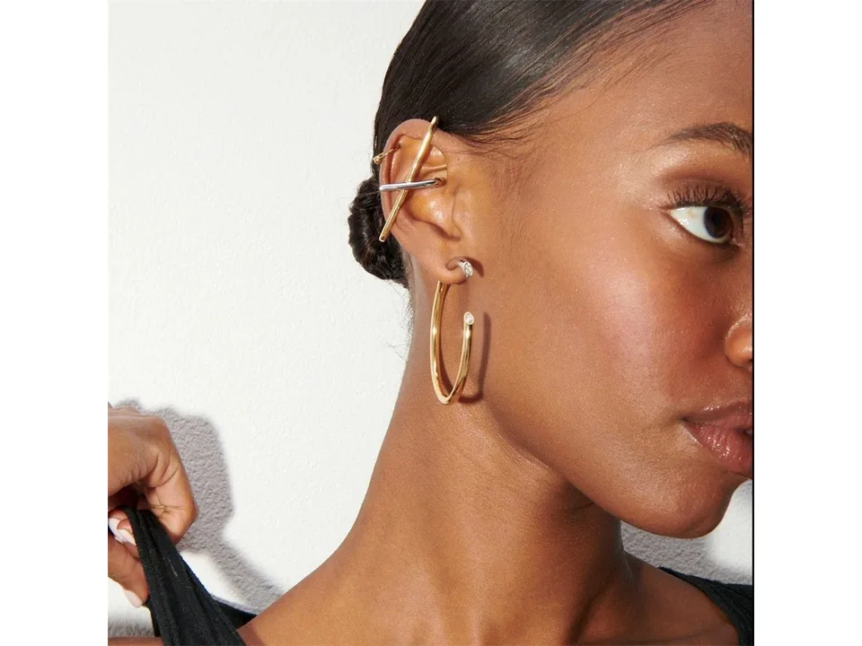 A model wearing the two-tone hoop earrings on her ear.