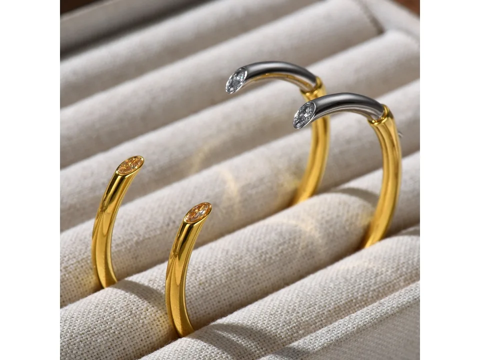 Close-up of the two-tone hoop earrings showing the crystal accents at the tips.