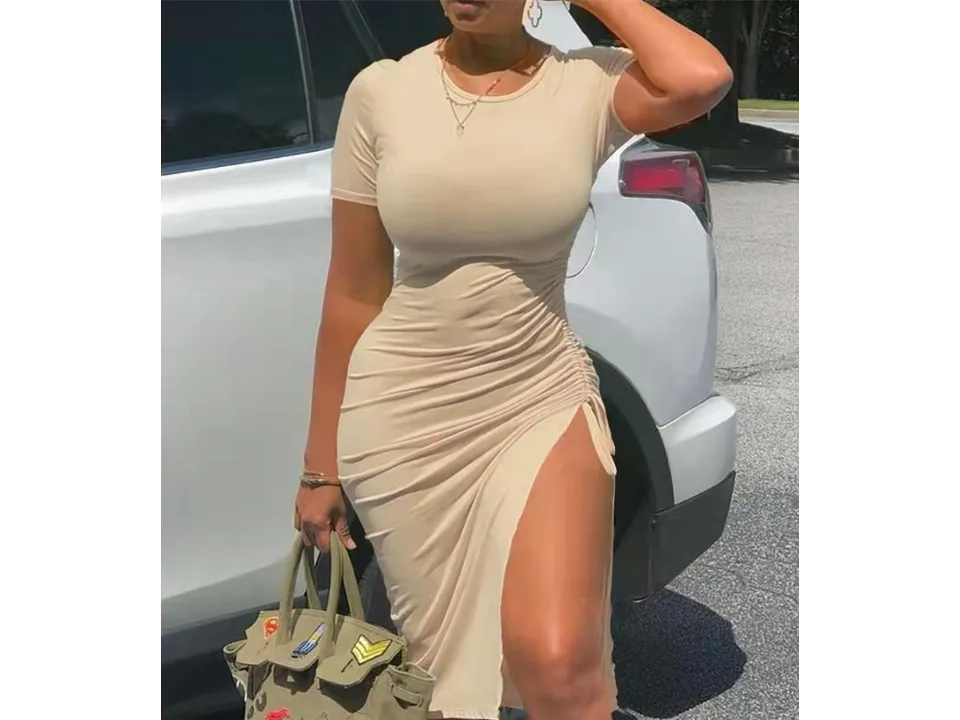 A woman wearing a beige short sleeve midi dress with a high side slit.
