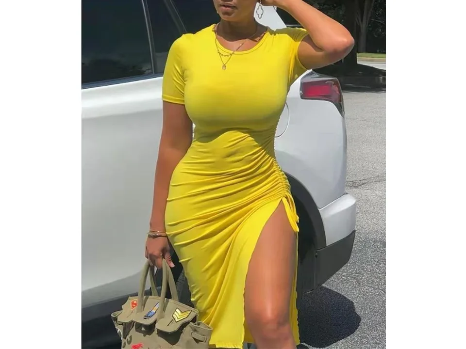A woman wearing a solid yellow short sleeve midi dress with a high side slit.