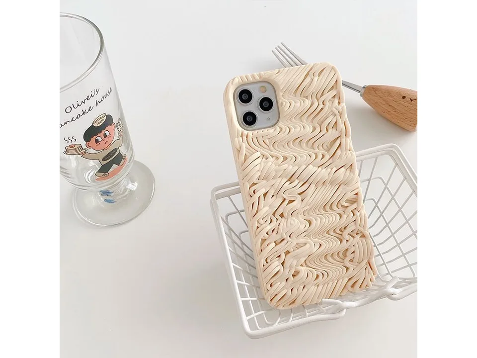 Noodle-textured phone case resting in a small white wire basket.