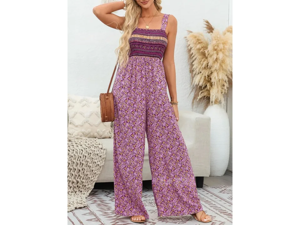 A woman wearing a purple floral sleeveless jumpsuit with a smocked bodice.
