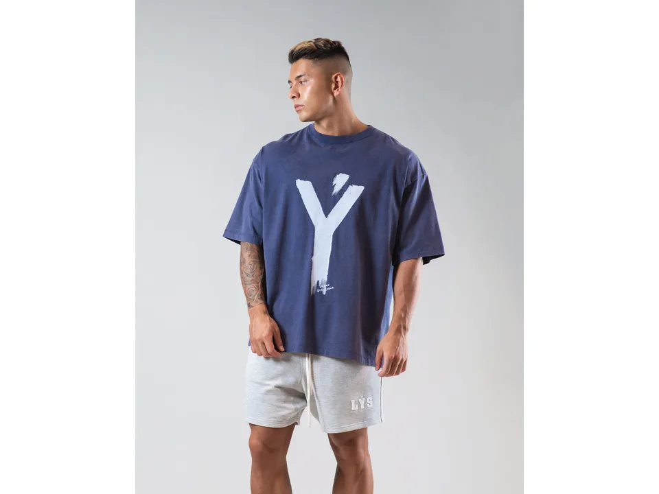 A man wearing an oversized blue t-shirt with a large white graphic print.